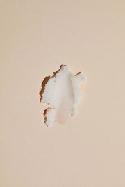 Close-up of a damaged drywall with a hole on a beige painted wall surface